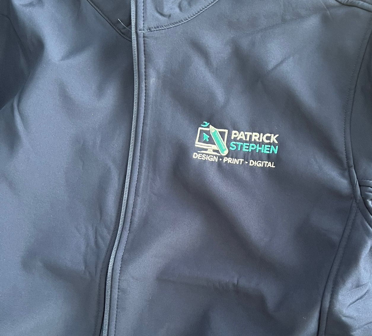 Black jacket with a “Patrick Stephen” logo on the chest.