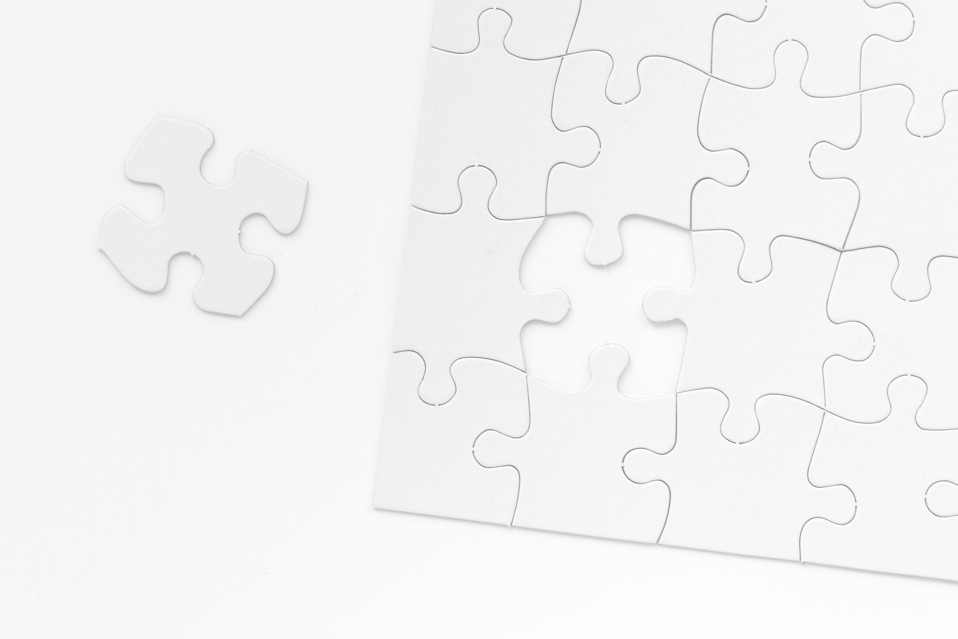 White puzzle with one missing piece, piece nearby.