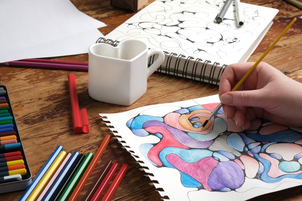 a group of people are sitting around a table painting a flower