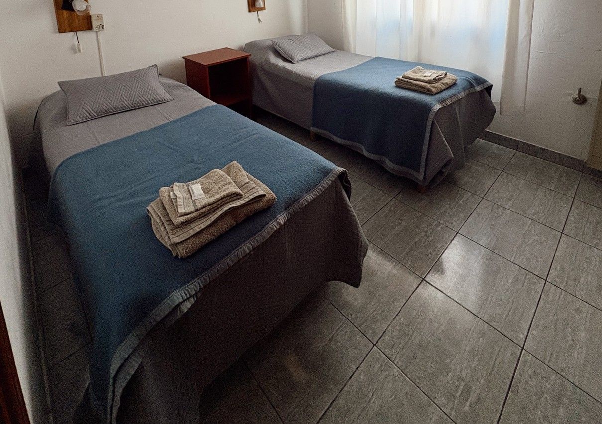 Habitación de hotel pequeña con dos camas bien hechas y toallas dobladas encima de cada una.