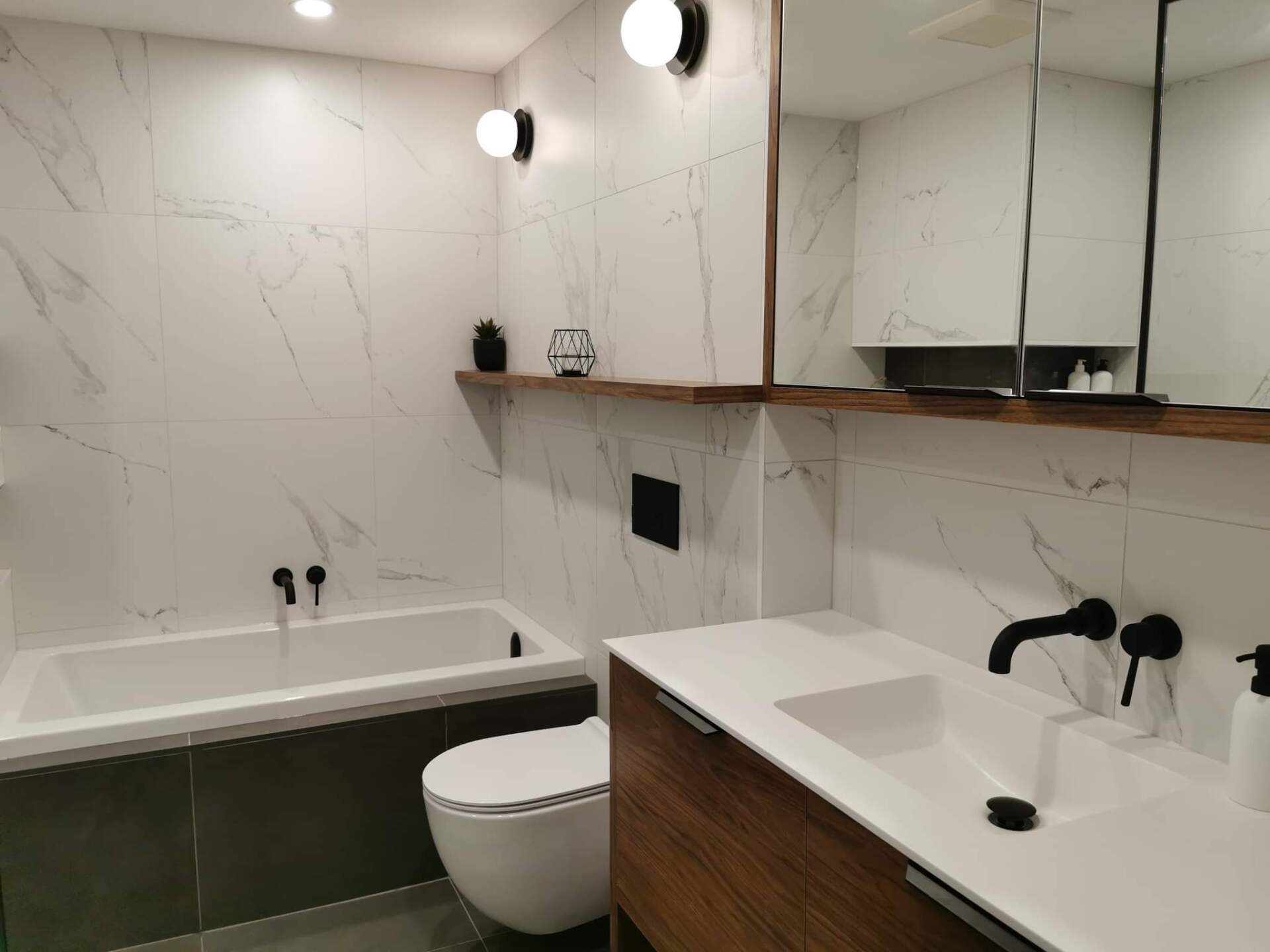 Une salle de bain avec baignoire , WC , lavabo et miroir.