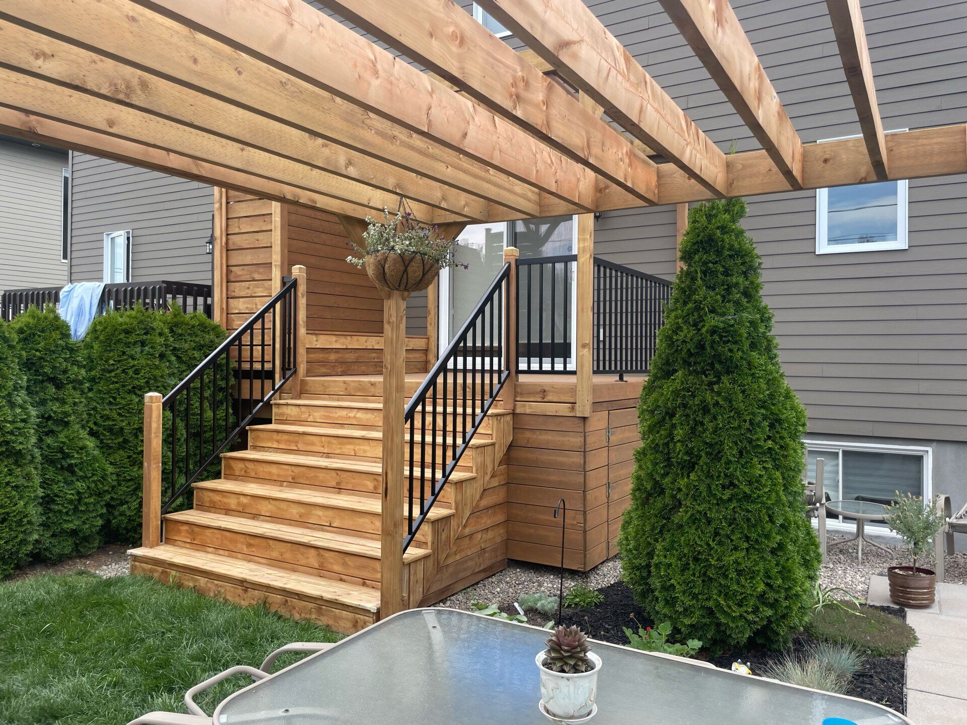 Une terrasse en bois avec des escaliers et une pergola dans la cour d'une maison.