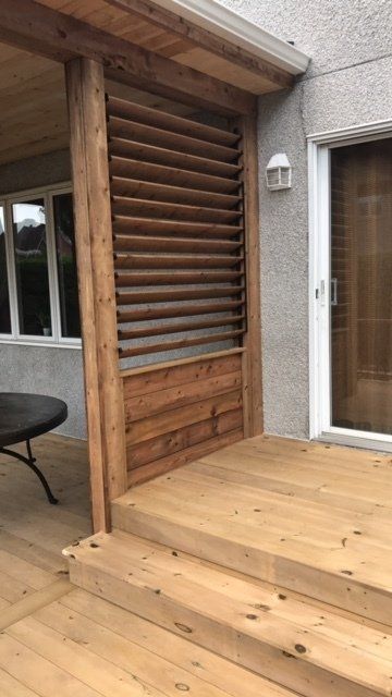 Une terrasse en bois avec des escaliers et une table devant une maison.