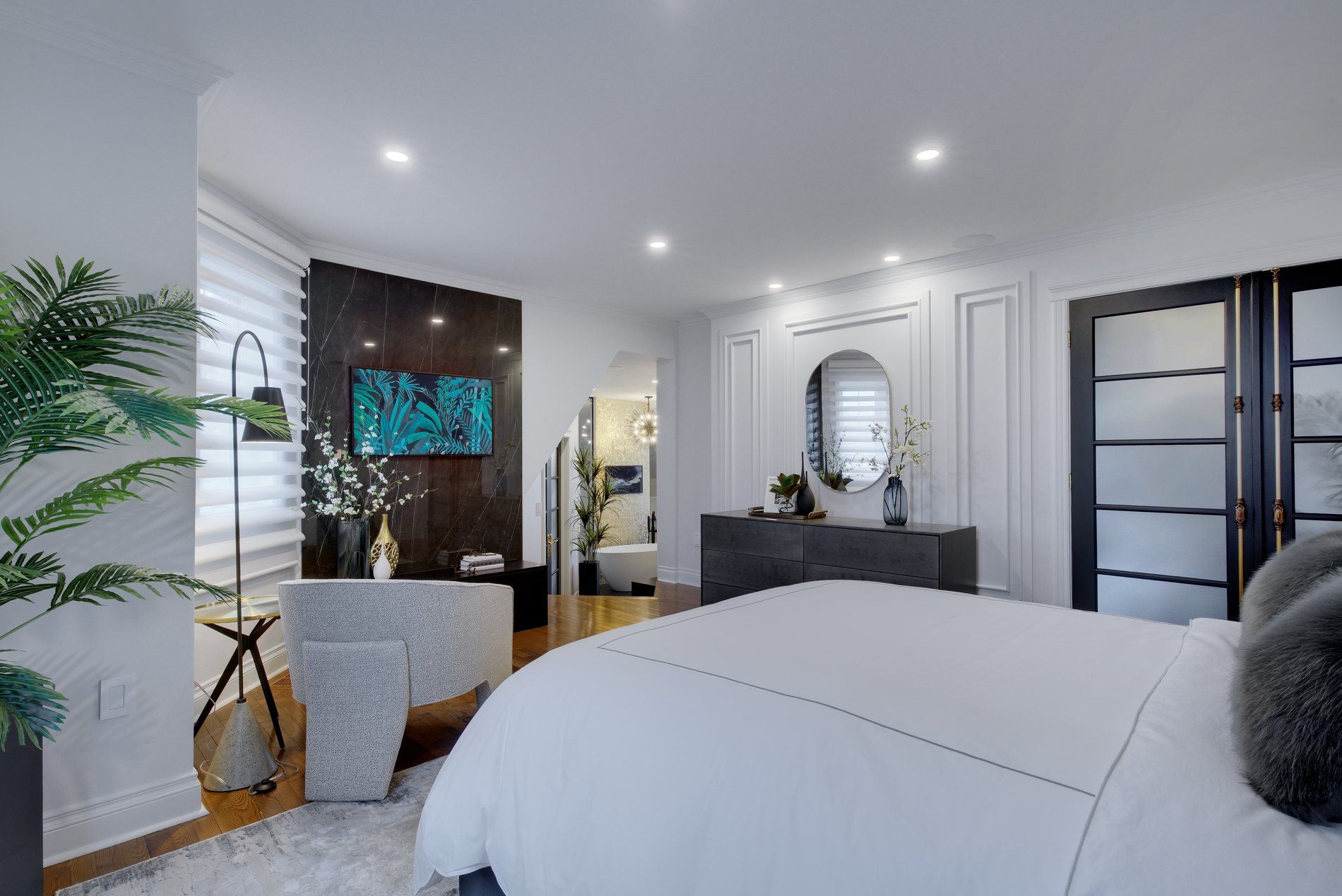 Une chambre avec un grand lit, une commode, un miroir et une télévision.