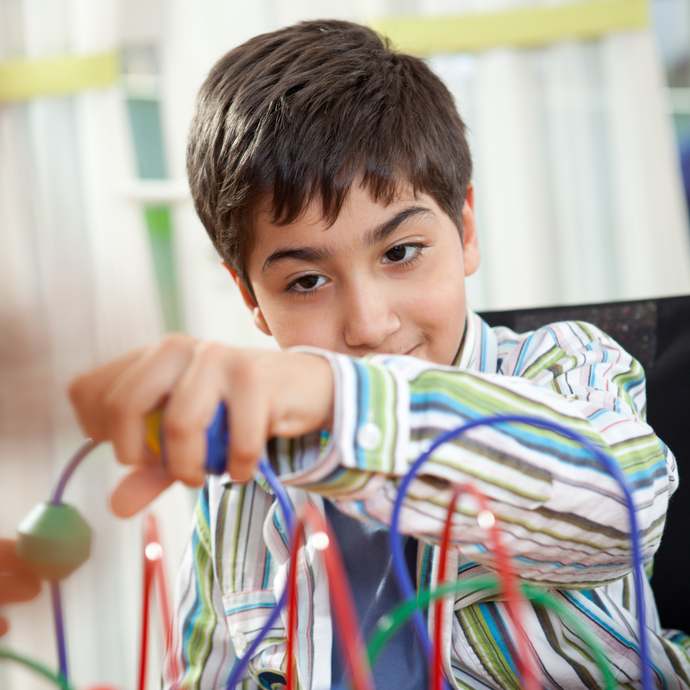 A young person in a striped shirt plays with a multi-colored bead maze toy.