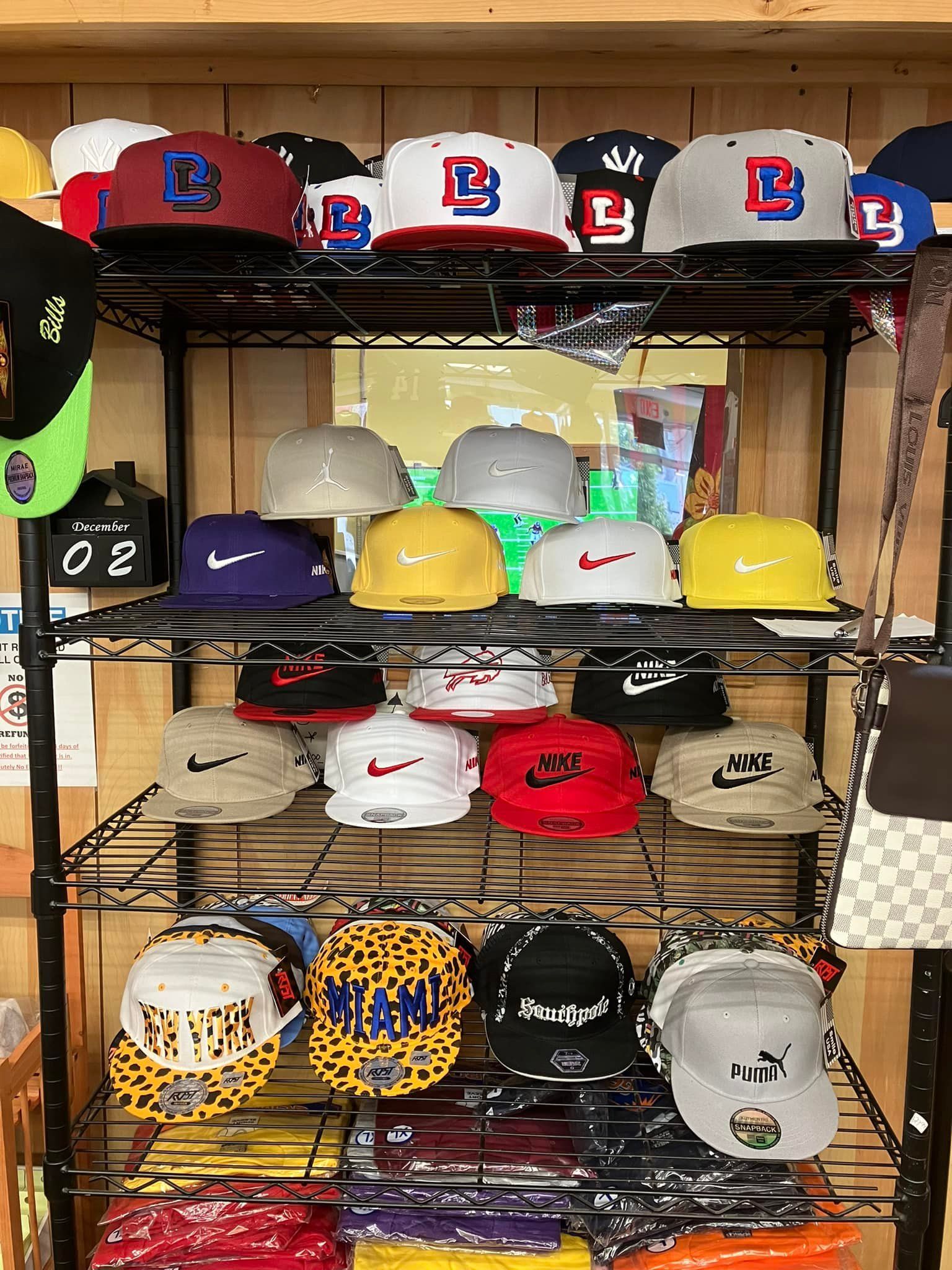 A retail display shelf stocked with many colorful baseball caps featuring various logos and patterns.