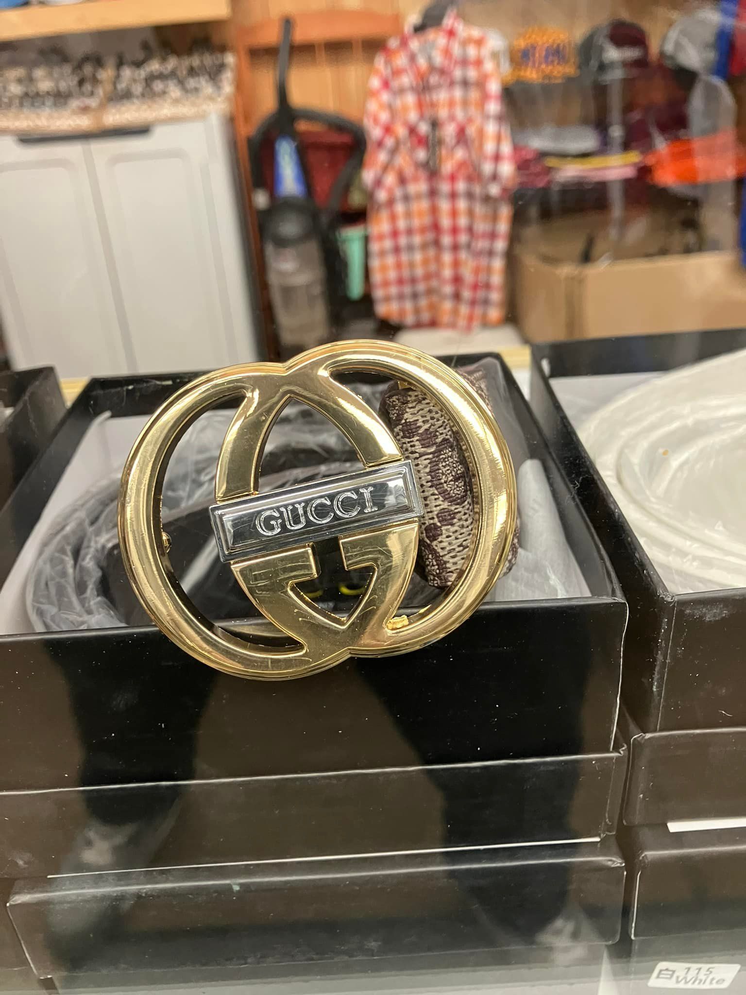 A Gucci belt with a prominent gold-tone, interlocking GG logo buckle displayed in an open black box.