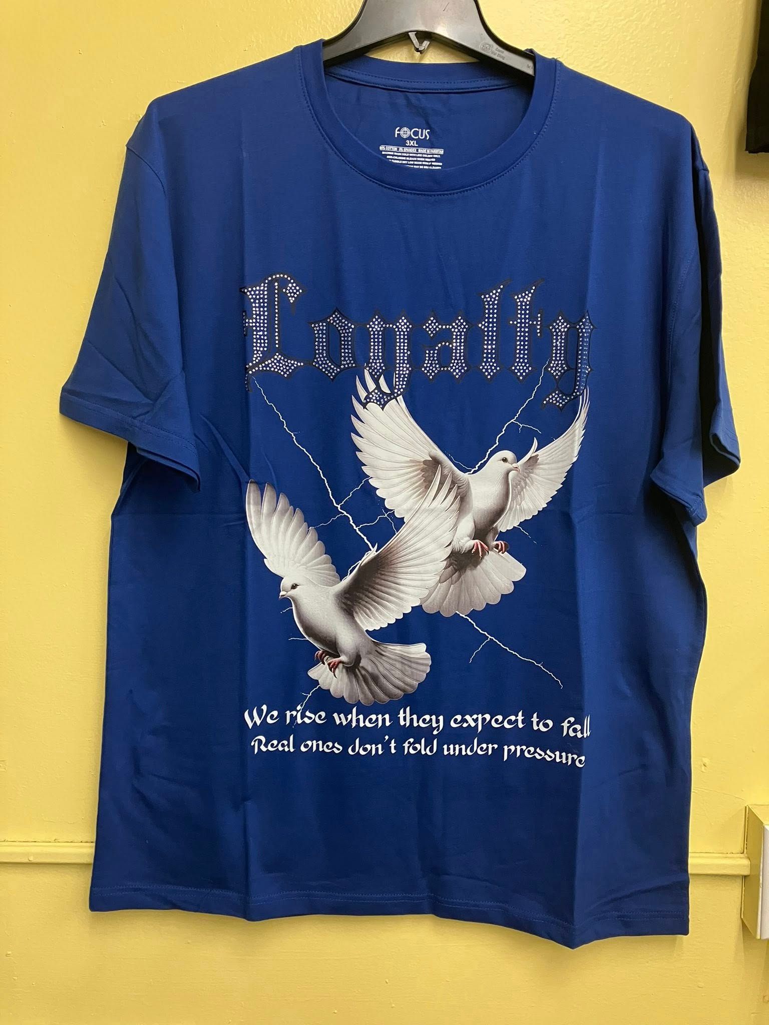 A blue t-shirt hanging on a hanger features the word "Loyalty" above two white doves in flight and printed text below.