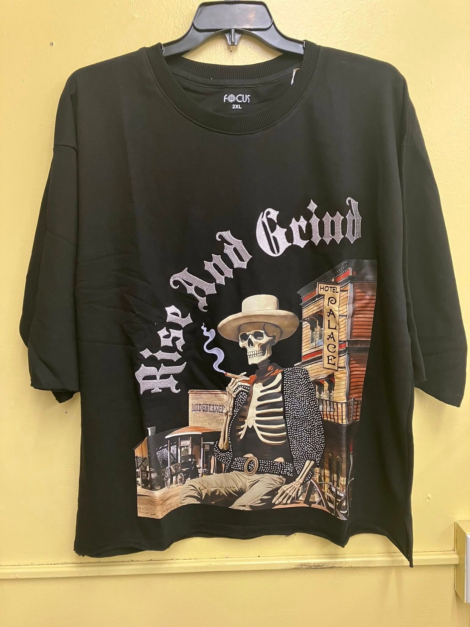 A black graphic t-shirt featuring a skeletal figure wearing a cowboy hat and smoking in front of a Western-style building.