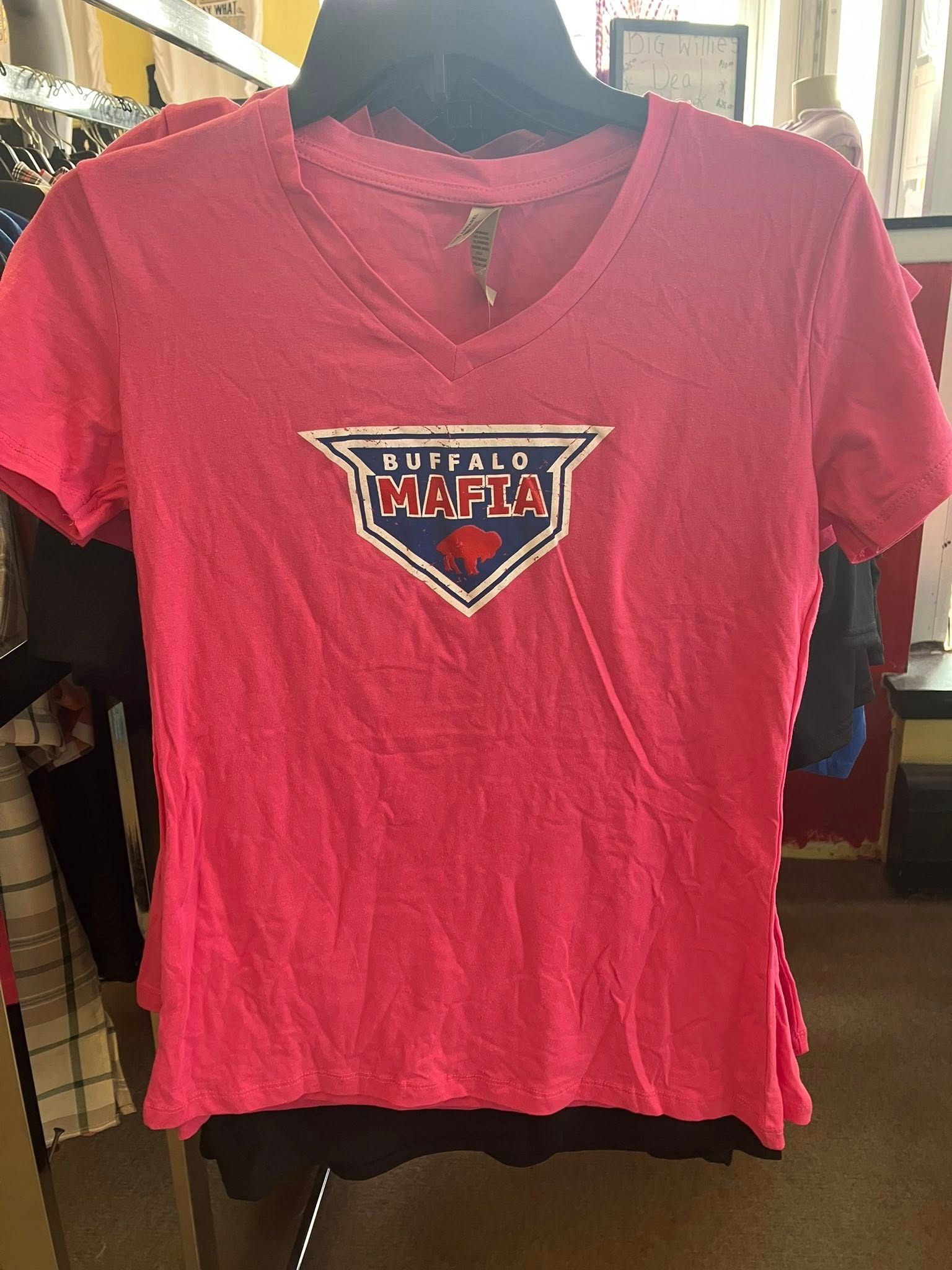 A bright pink, v-neck Buffalo Mafia graphic t-shirt on a hanger in a store.