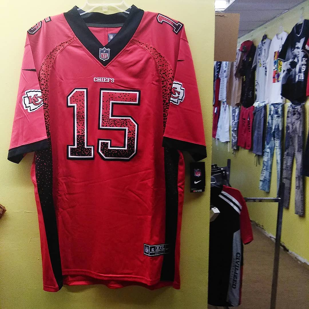 A red and black Kansas City Chiefs jersey with the number 15 hanging in a clothing store.