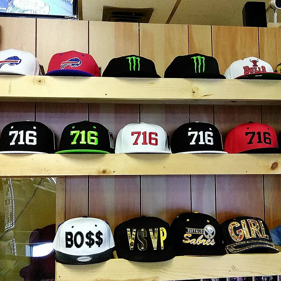 Display shelves holding various baseball caps featuring team logos, the area code 
