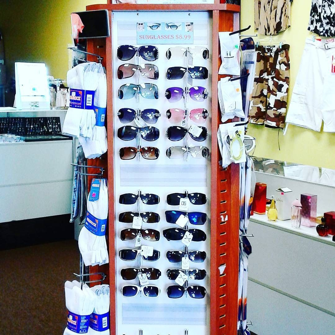 A revolving display stand stocked with various sunglasses and packages of socks inside a retail store.