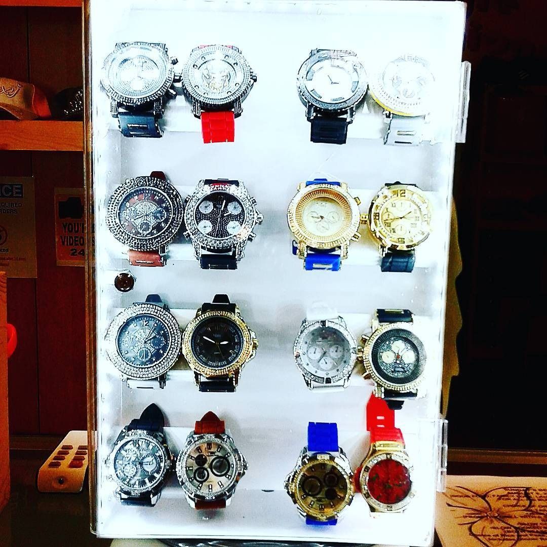A retail display case holding sixteen wristwatches arranged in four rows, featuring various colors and band styles.