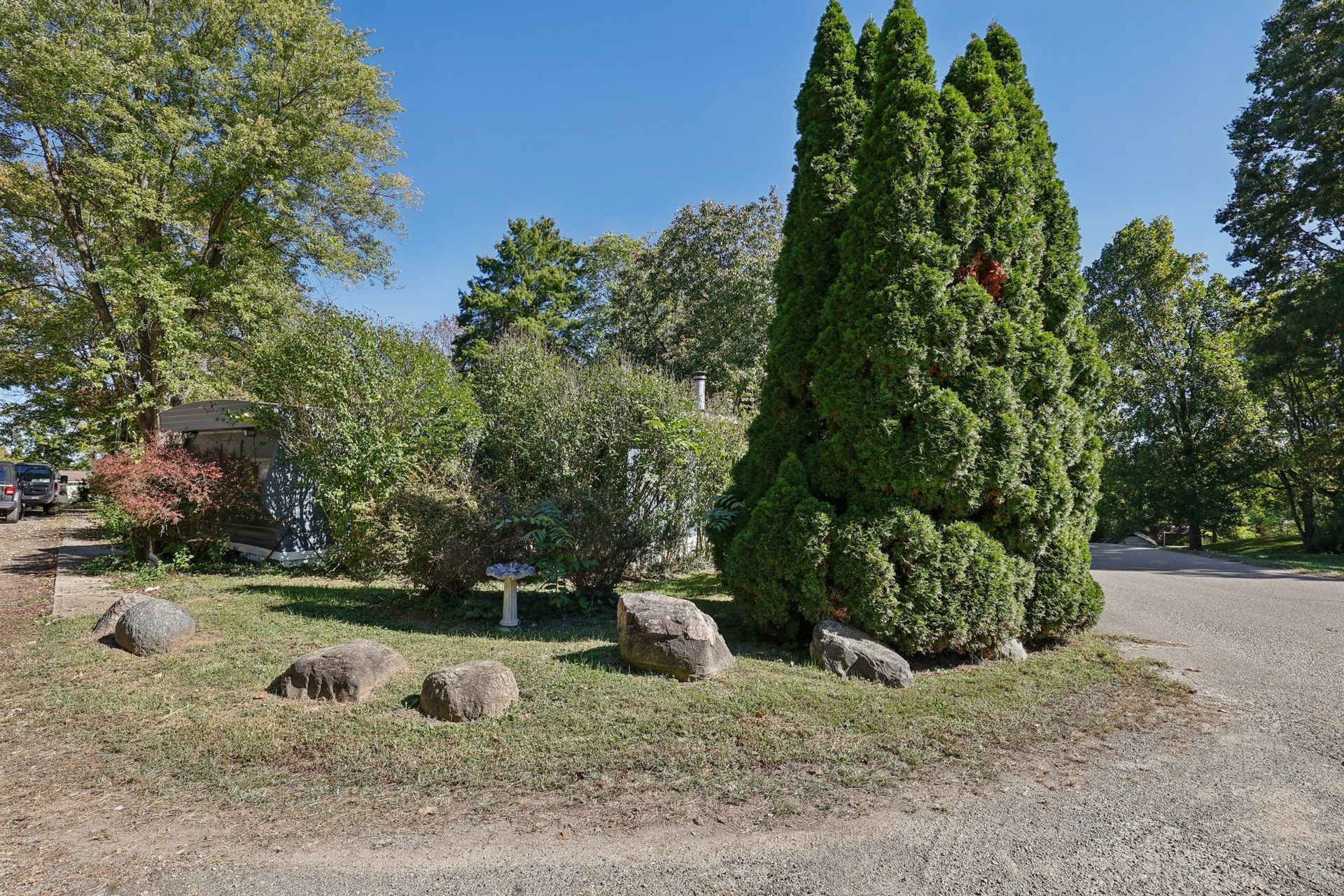 Landscaped community entrance with mature trees and decorative stone.