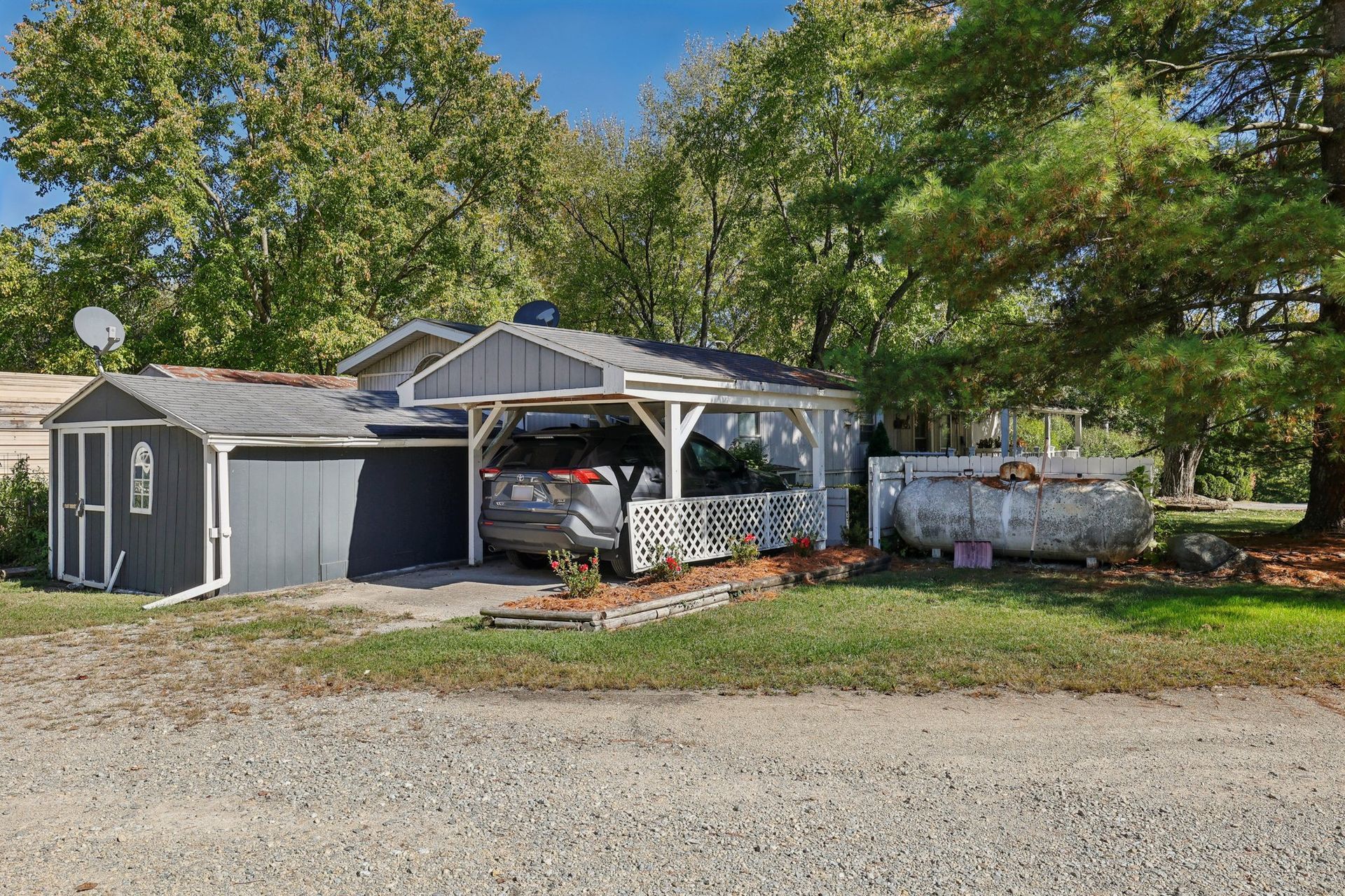 Manufactured home with covered parking and storage shed.