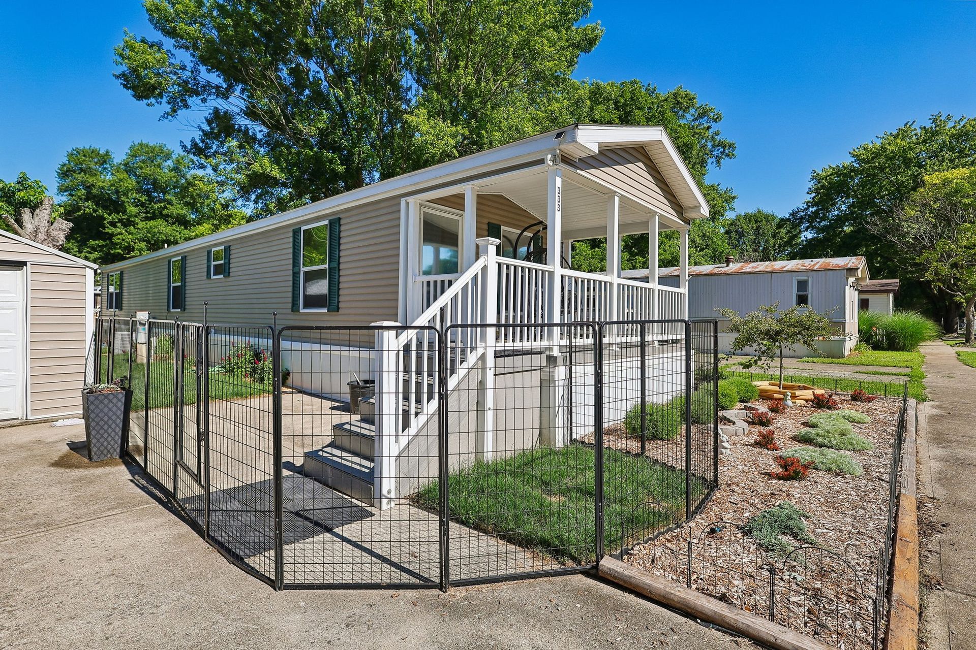 Manufactured home with covered porch, fenced entry, and landscaped yard.
