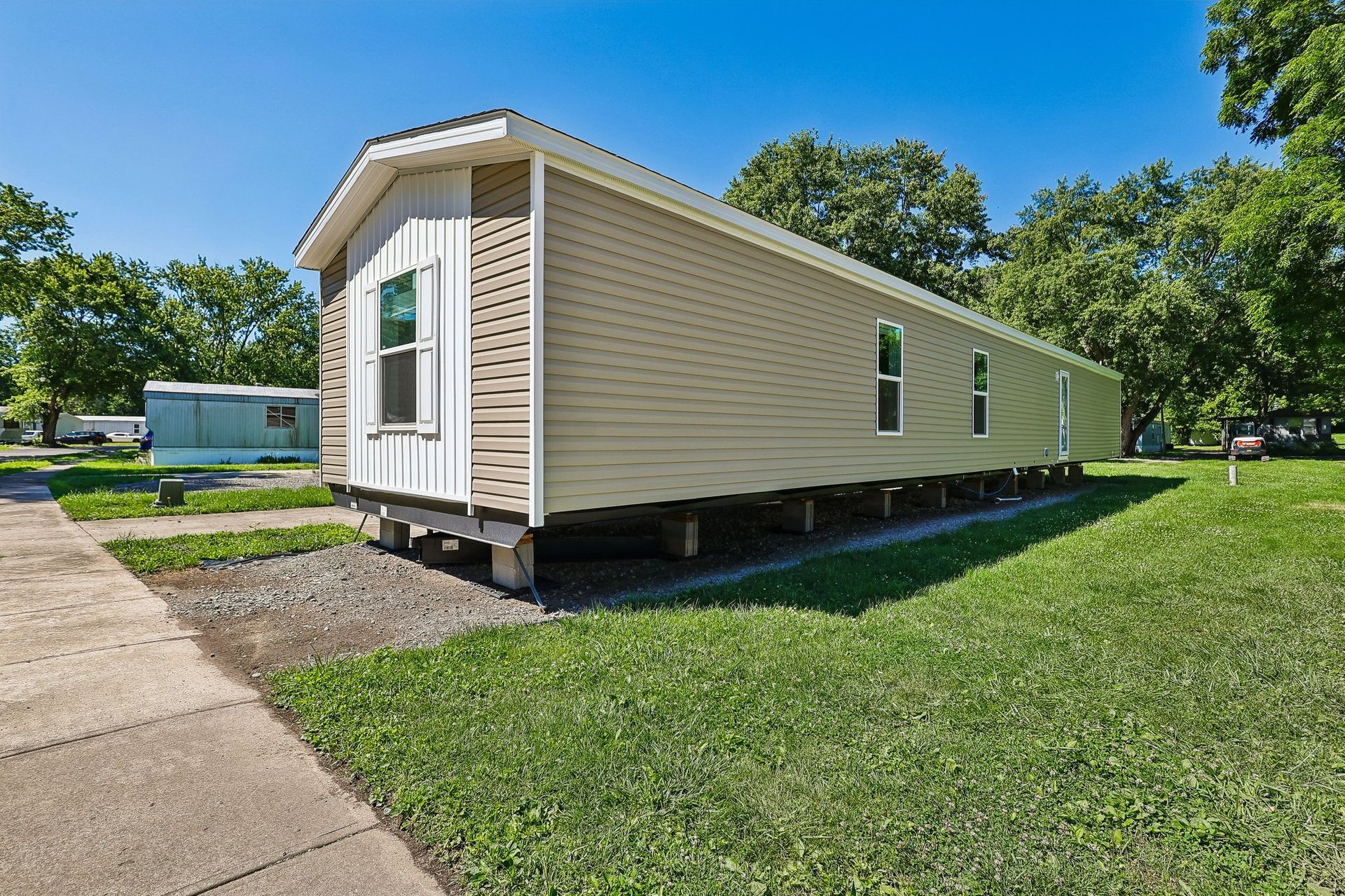 Corner view of manufactured home with vinyl siding and private lot.