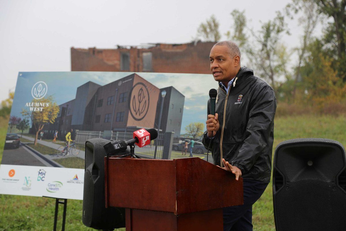 Dr. Troy Nash at the podium, the Alumnus Gardens West rendering behind him, at the groundbreaking.