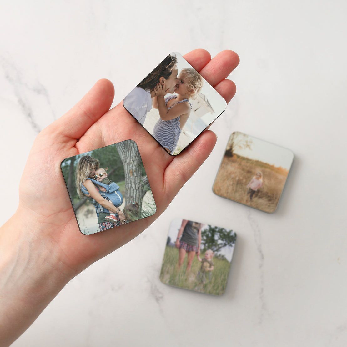 A person is holding three square magnets in their hand