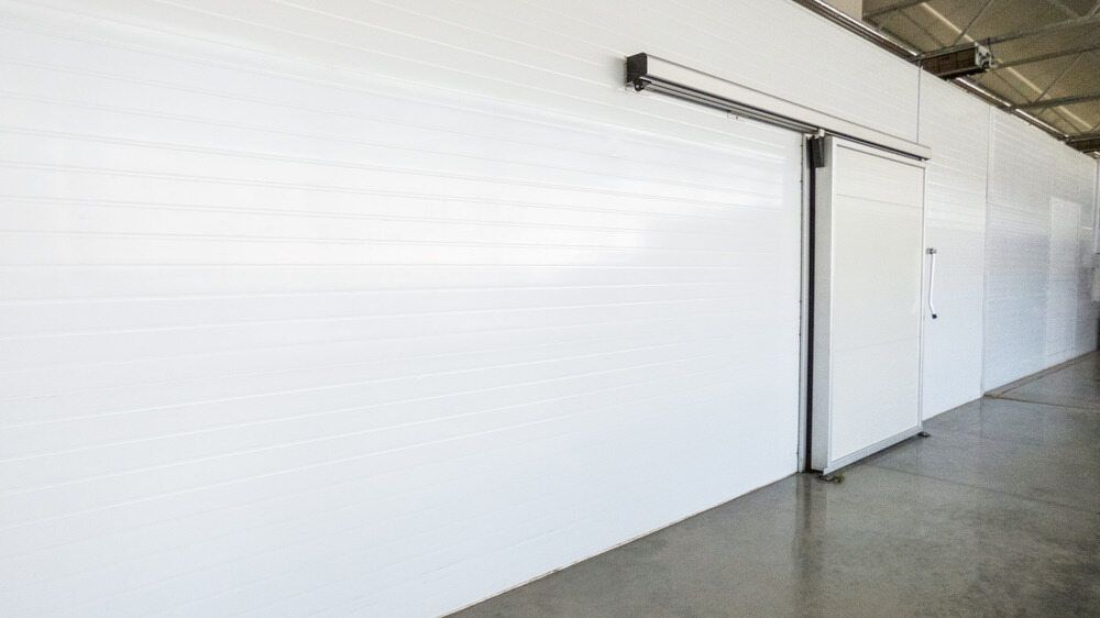 A White Wall With a Sliding Door in a Warehouse — Noosa Refrigeration & Air-conditioning in Coolum, QLD