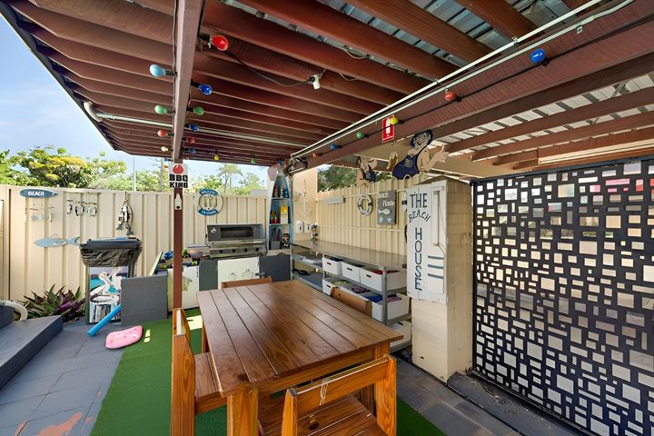 Covered outdoor patio with wooden picnic table, string lights, and a lattice privacy wall