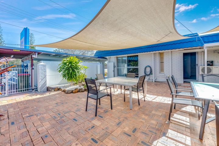 Covered outdoor patio with wooden picnic table, string lights, and a lattice privacy wall