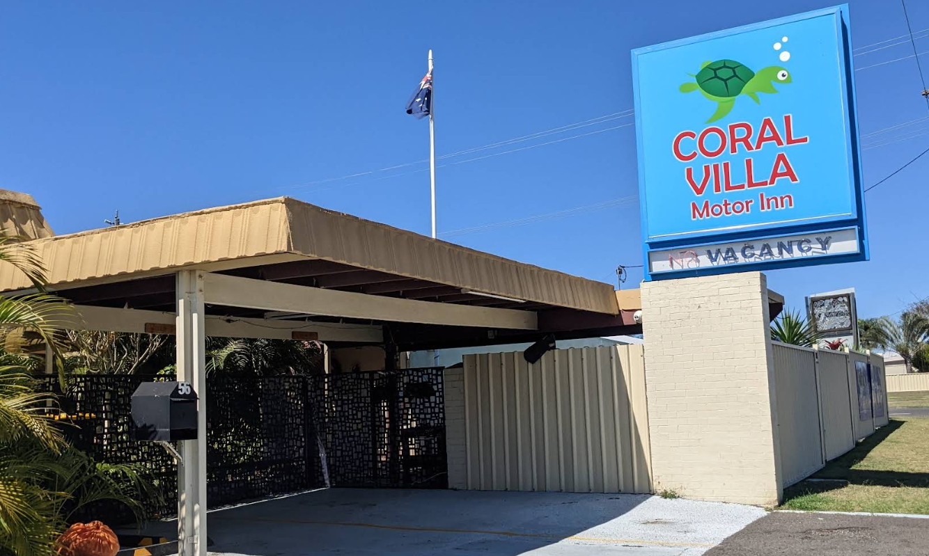 Coral Villa sign beside a tan building under a clear blue sky