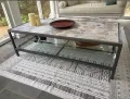 Stone-top coffee table with black metal frame on a patterned rug in a living room