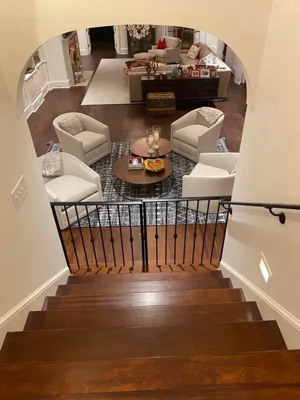 Staircase overlooking a living room with a coffee table, chairs, sofa, and hardwood floors