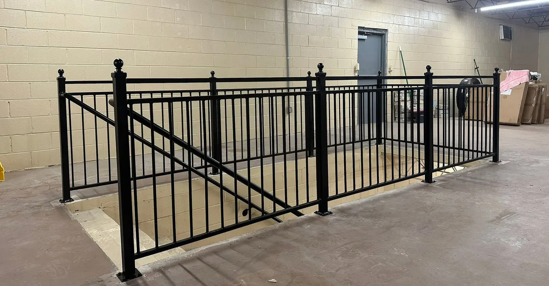 Black metal railing enclosing a concrete ramp in a beige indoor hallway