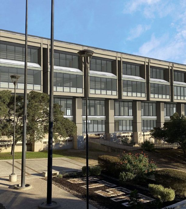 UTSA John Peace Library with large windows, trees, and a landscaped courtyard under a blue sky