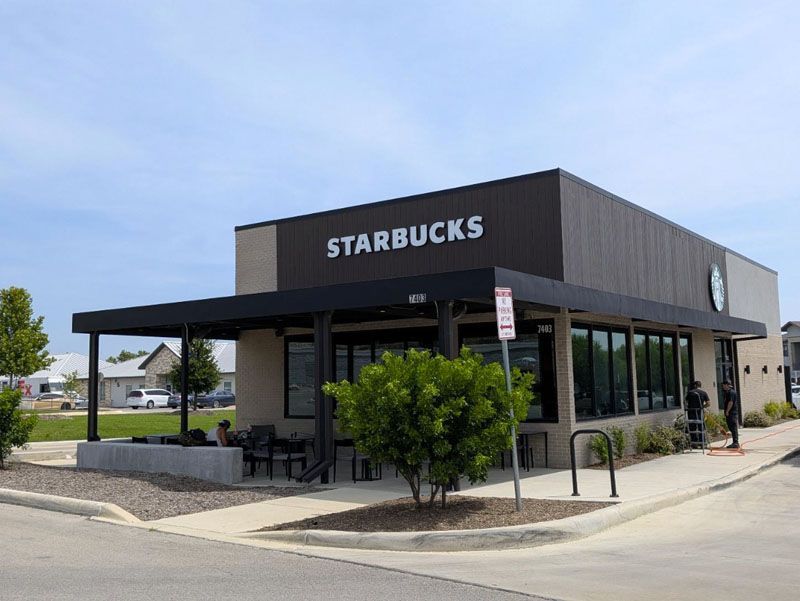 Starbucks storefront with outdoor seating on a sunny street corner