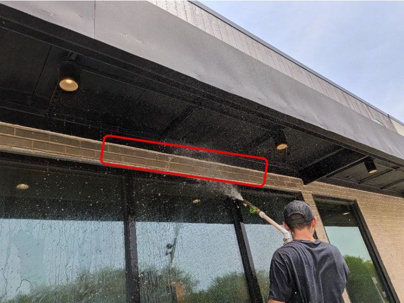 Worker points at a red-outlined area under a building awning