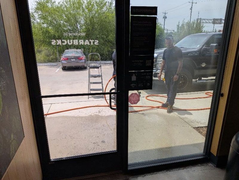 Glass storefront doors with a parked car outside and a person standing near the entrance