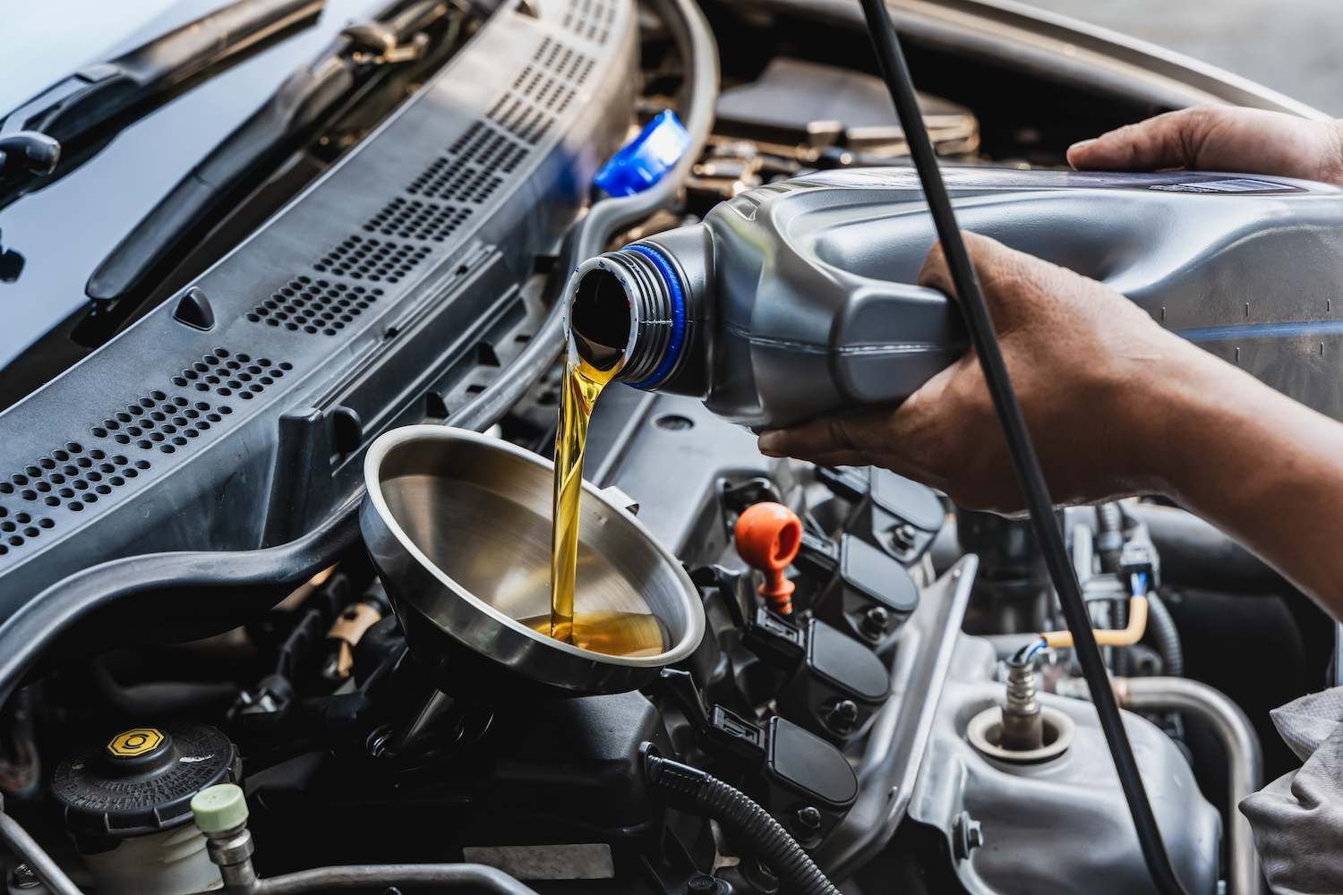 A Person is Pouring Oil Into a Car Engine — Mid Coast Bearing Centre in Wauchope, NSW