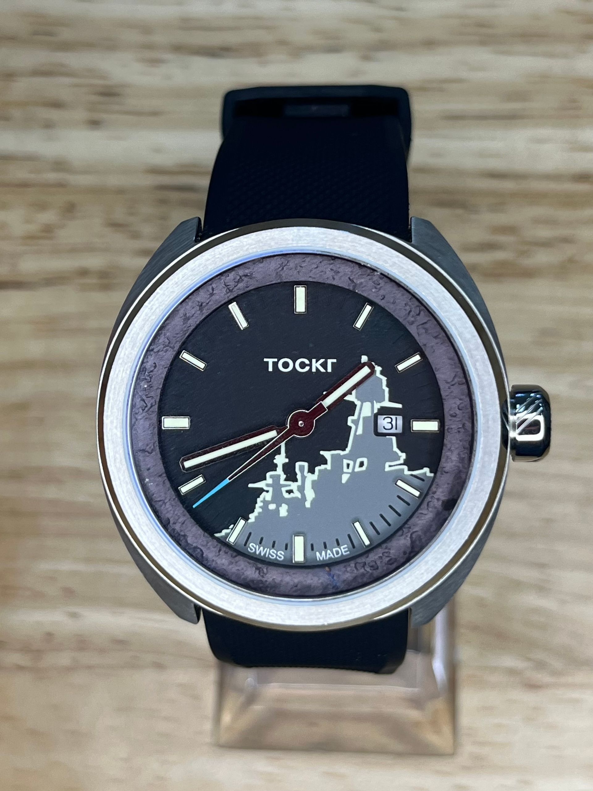 A dark gray Tockr watch with a map design on its face and a black band.