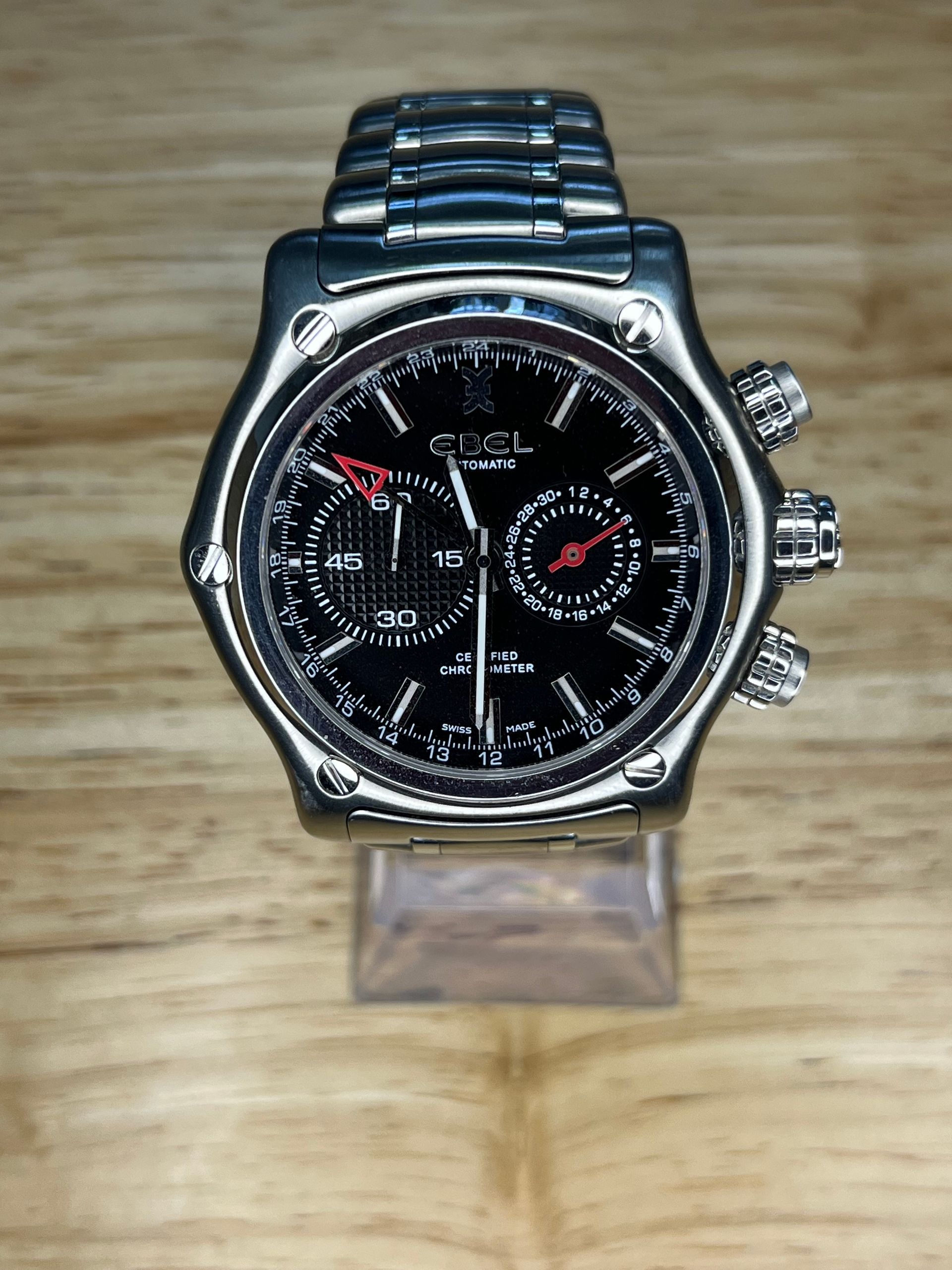 Silver wristwatch with black face on a wooden surface.