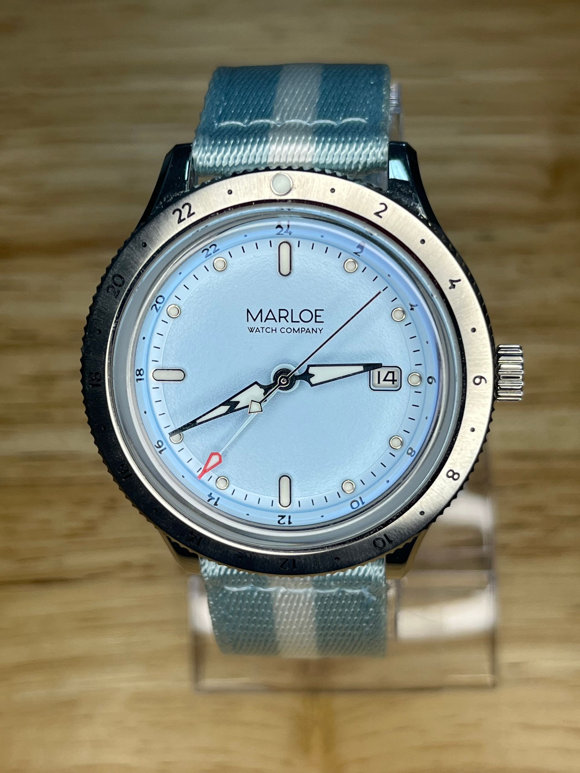 Light blue watch with a light blue and white striped band.