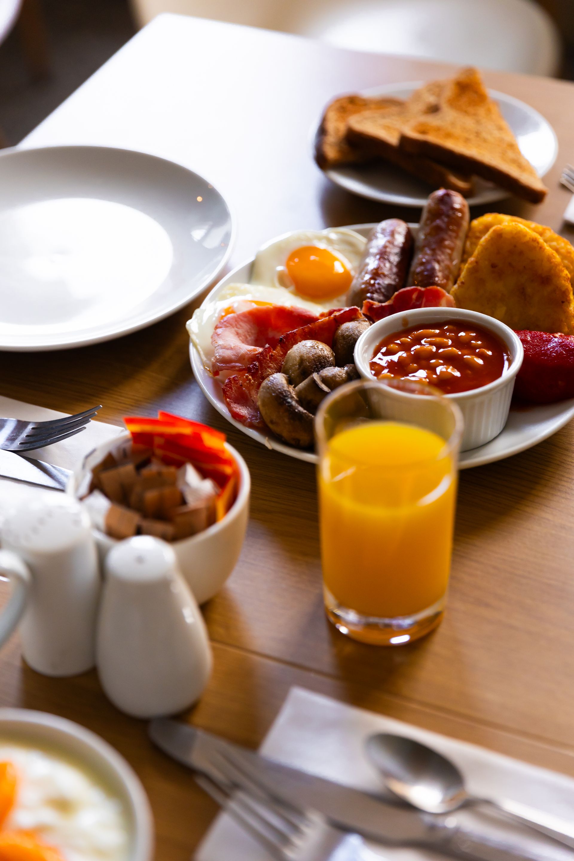 A table topped with plates of food and a glass of orange juice.