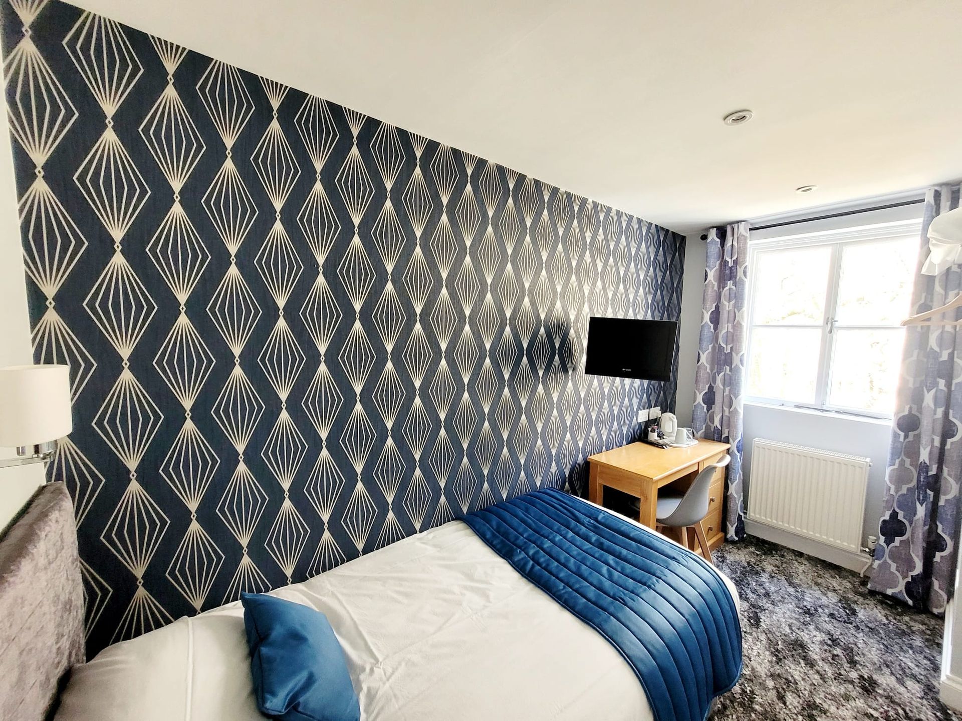 A hotel room with a bed , desk and television