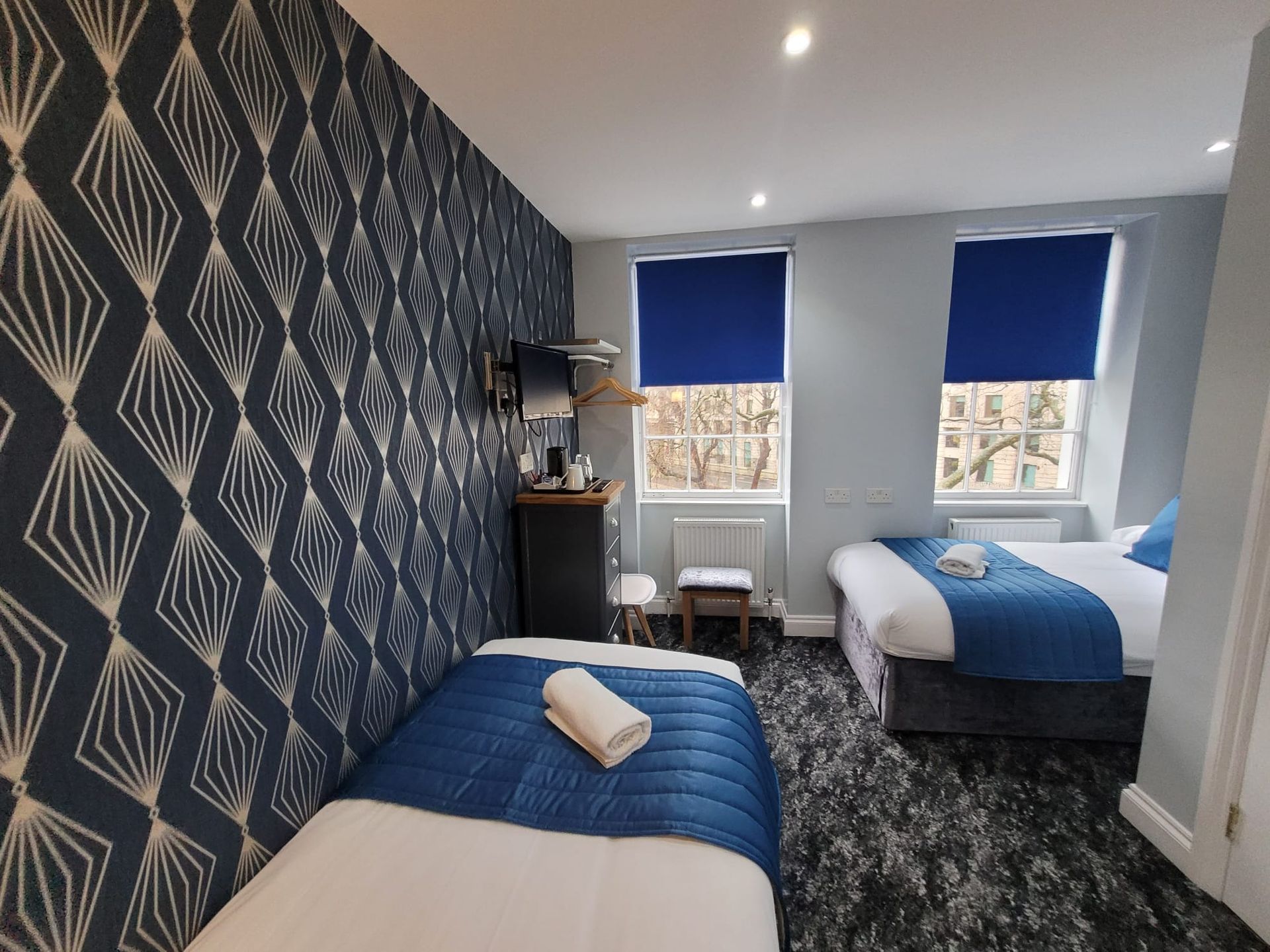 A hotel room with two beds and blue blinds