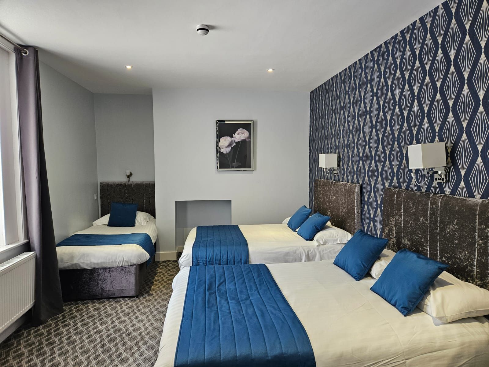 A hotel room with three beds and a picture on the wall.