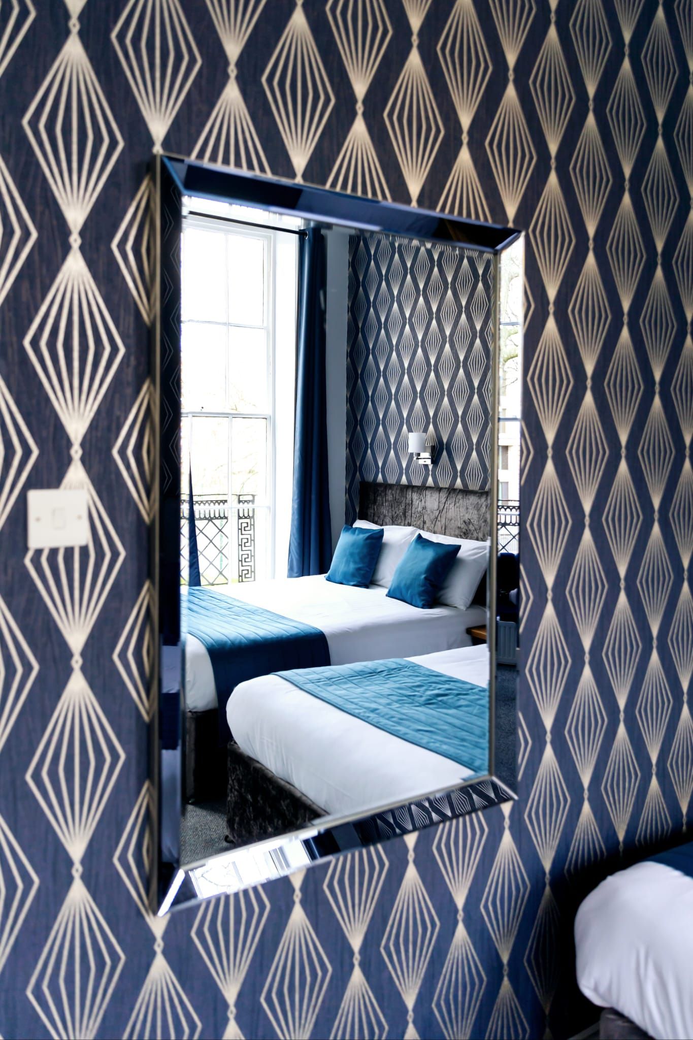 A hotel room with two beds and a mirror.