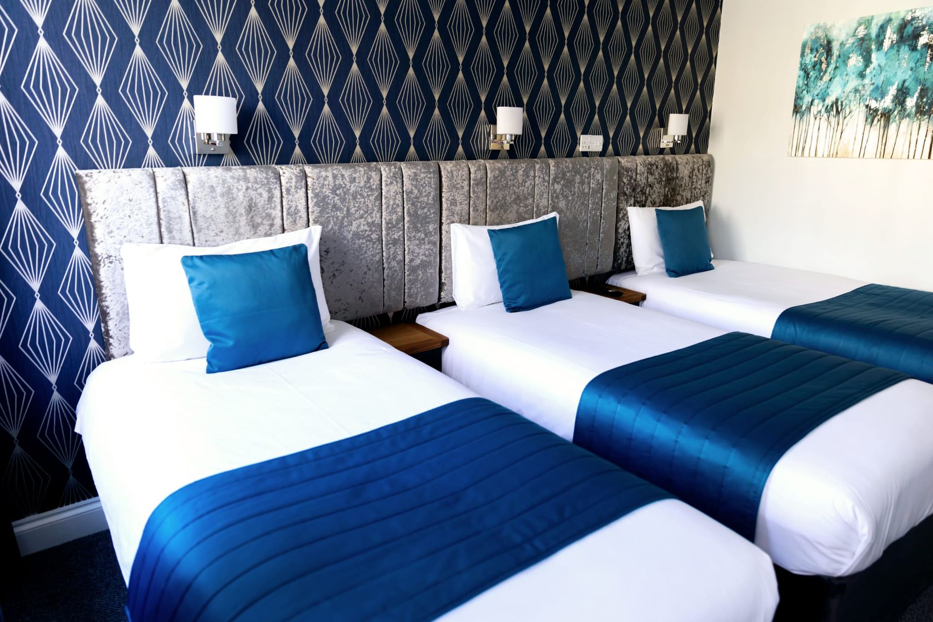 Three beds in a hotel room with blue blankets
