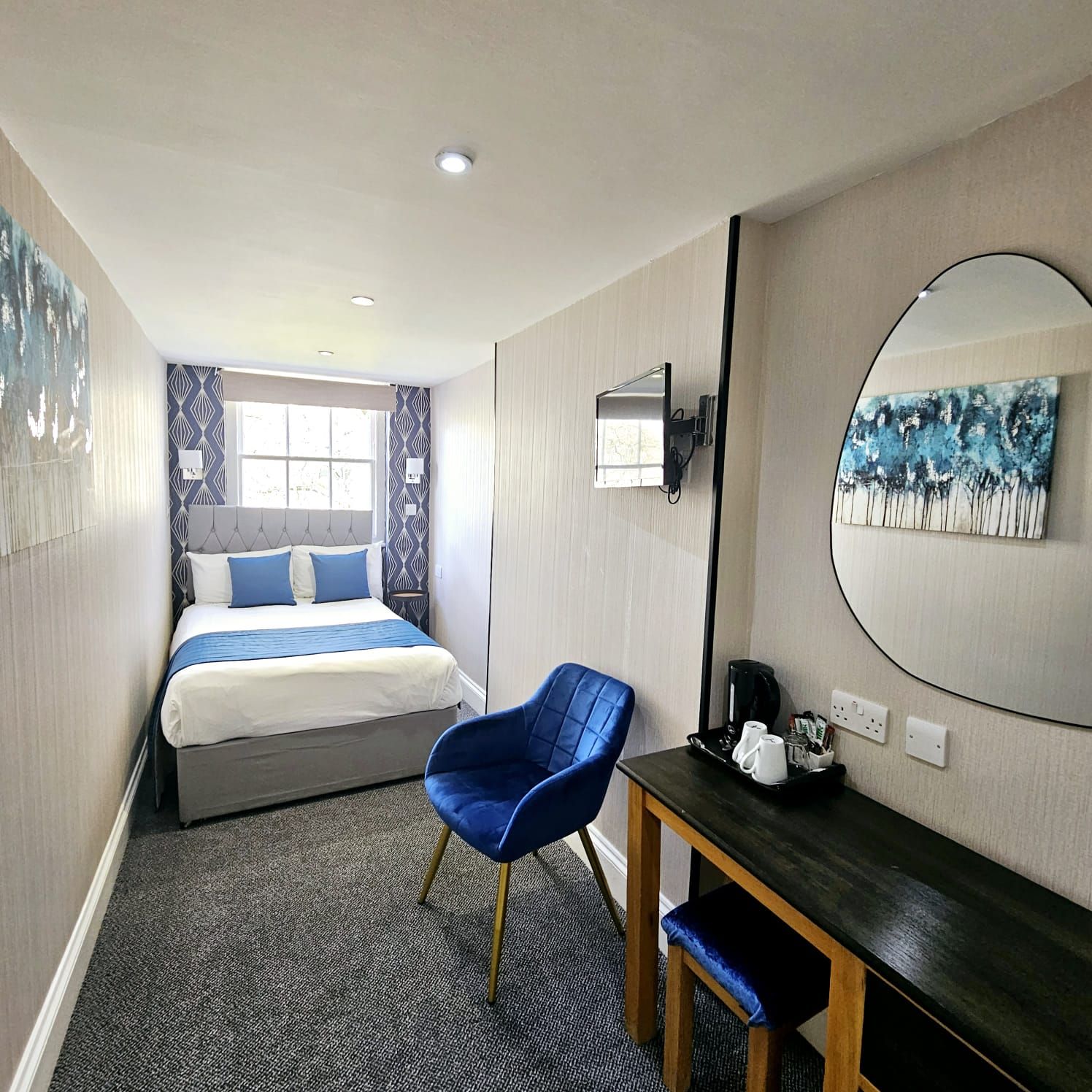 A hotel room with a bed , chair , desk and mirror
