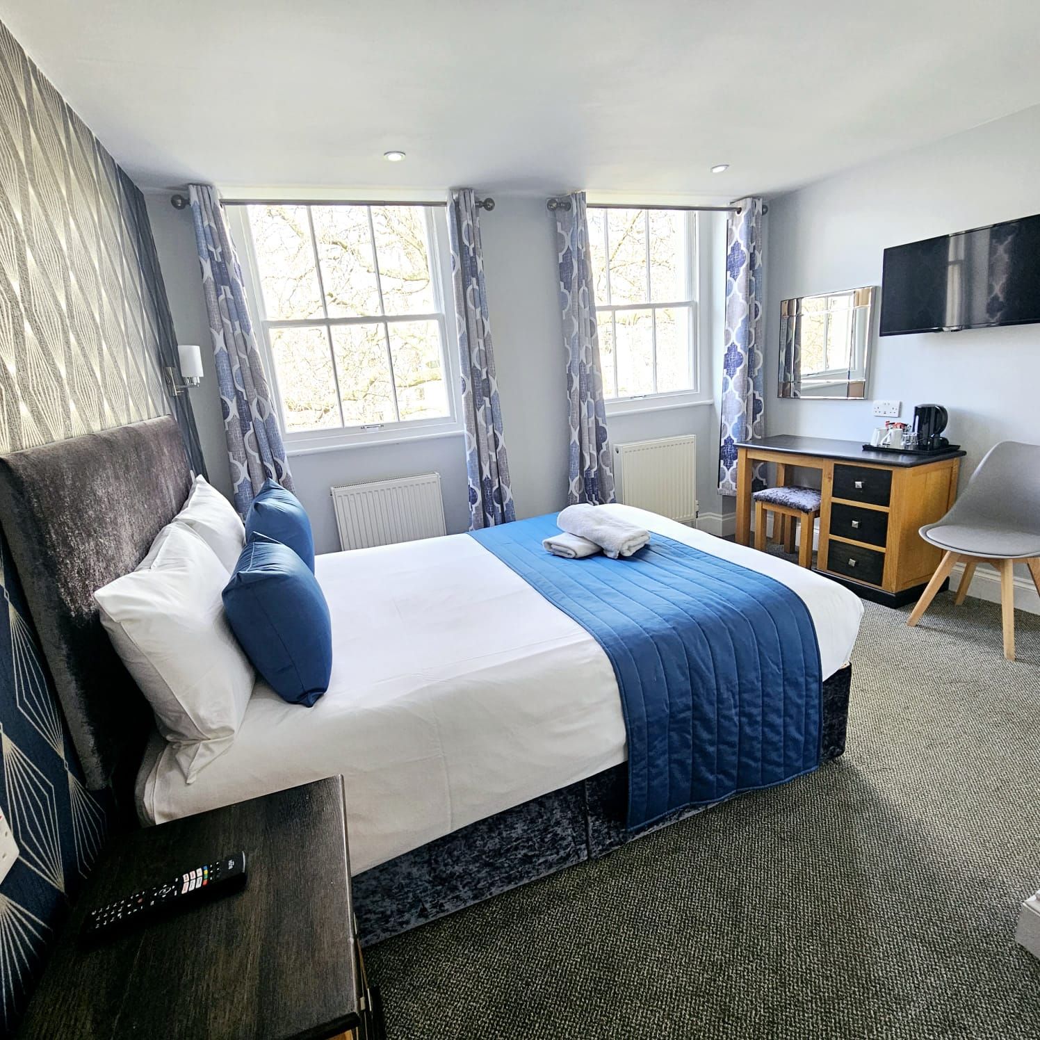 A hotel room with a bed , desk , chair and window.