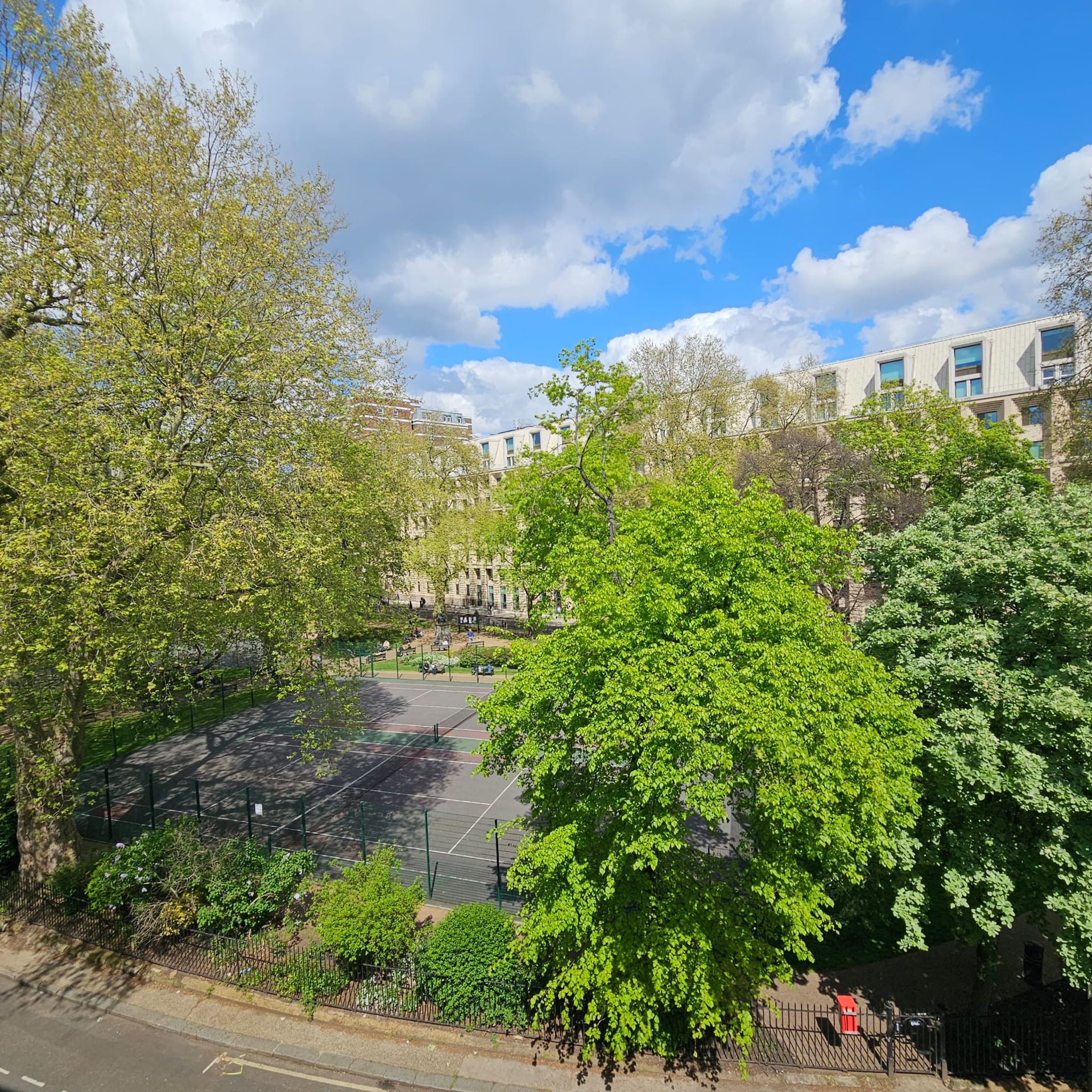 A view of a park with trees and a building in the background
