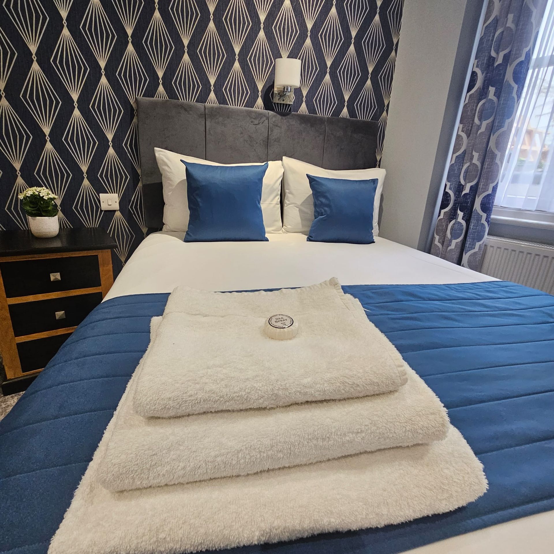 A bed with a blue blanket and white towels on it