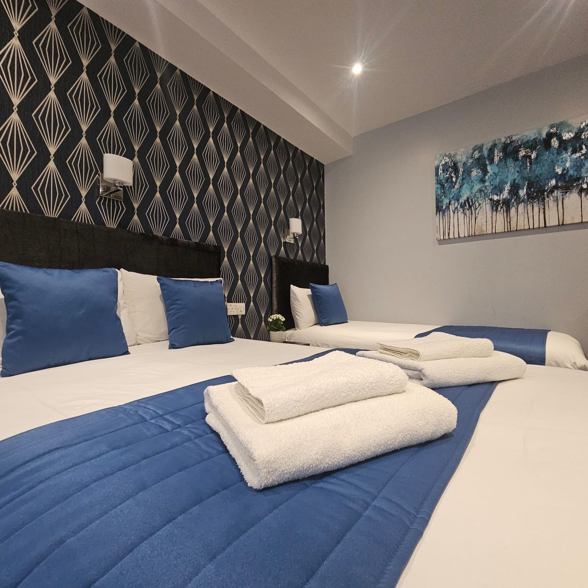 A hotel room with two beds and a painting on the wall